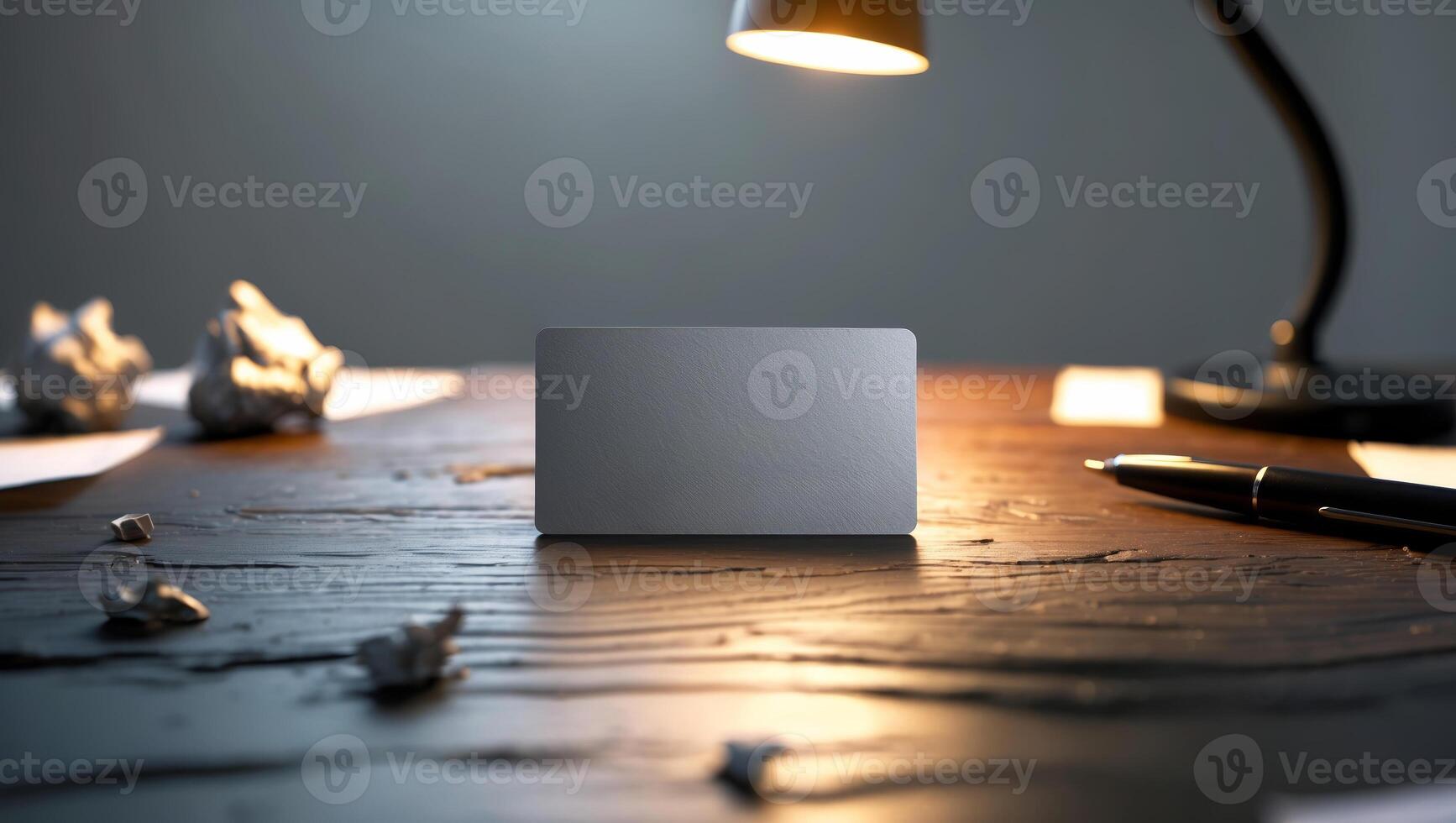 Stationery setup with a blank card on a wooden desk in a dimly lit room during nighttime photo
