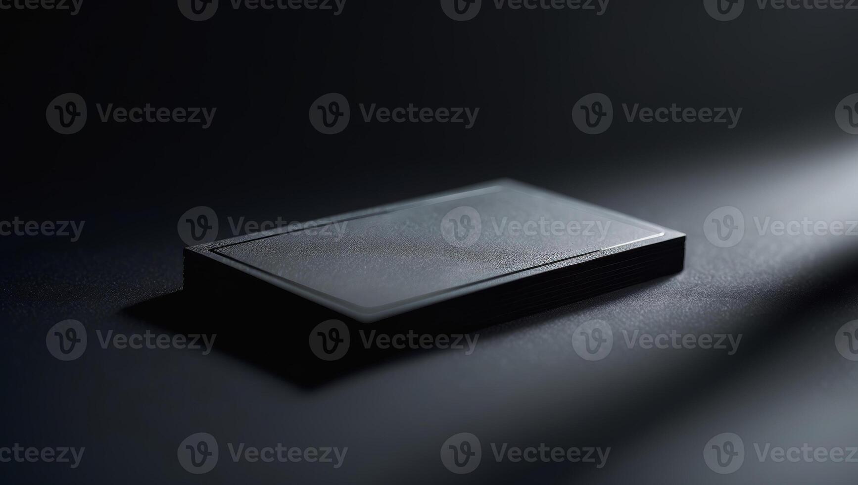 Black rectangular device rests on a dark surface, illuminated by a soft light in a minimalistic setting photo