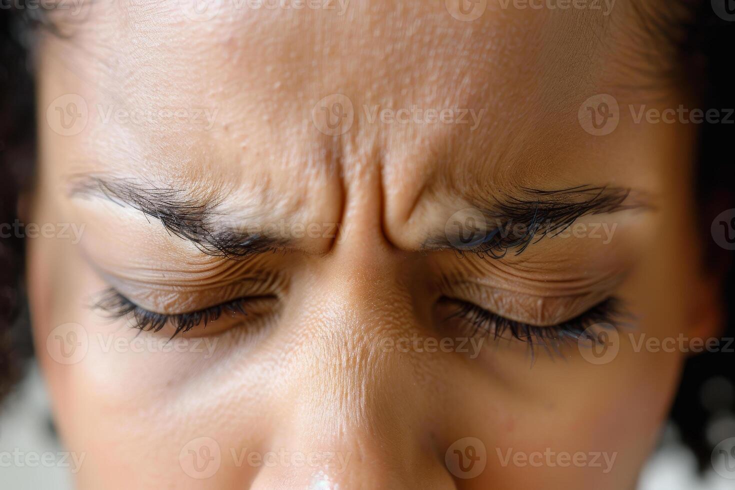 A woman with her eyes closed and her eyebrows raised photo