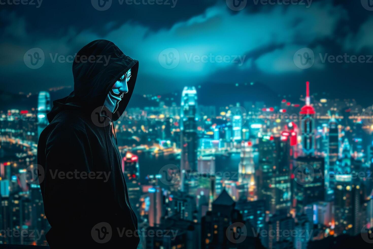 Anonymous hacker in black hoodie standing in front of cityscape at night photo