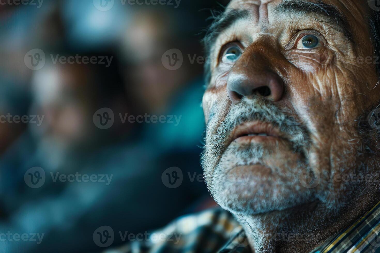 A man with a beard and gray hair is looking at something photo