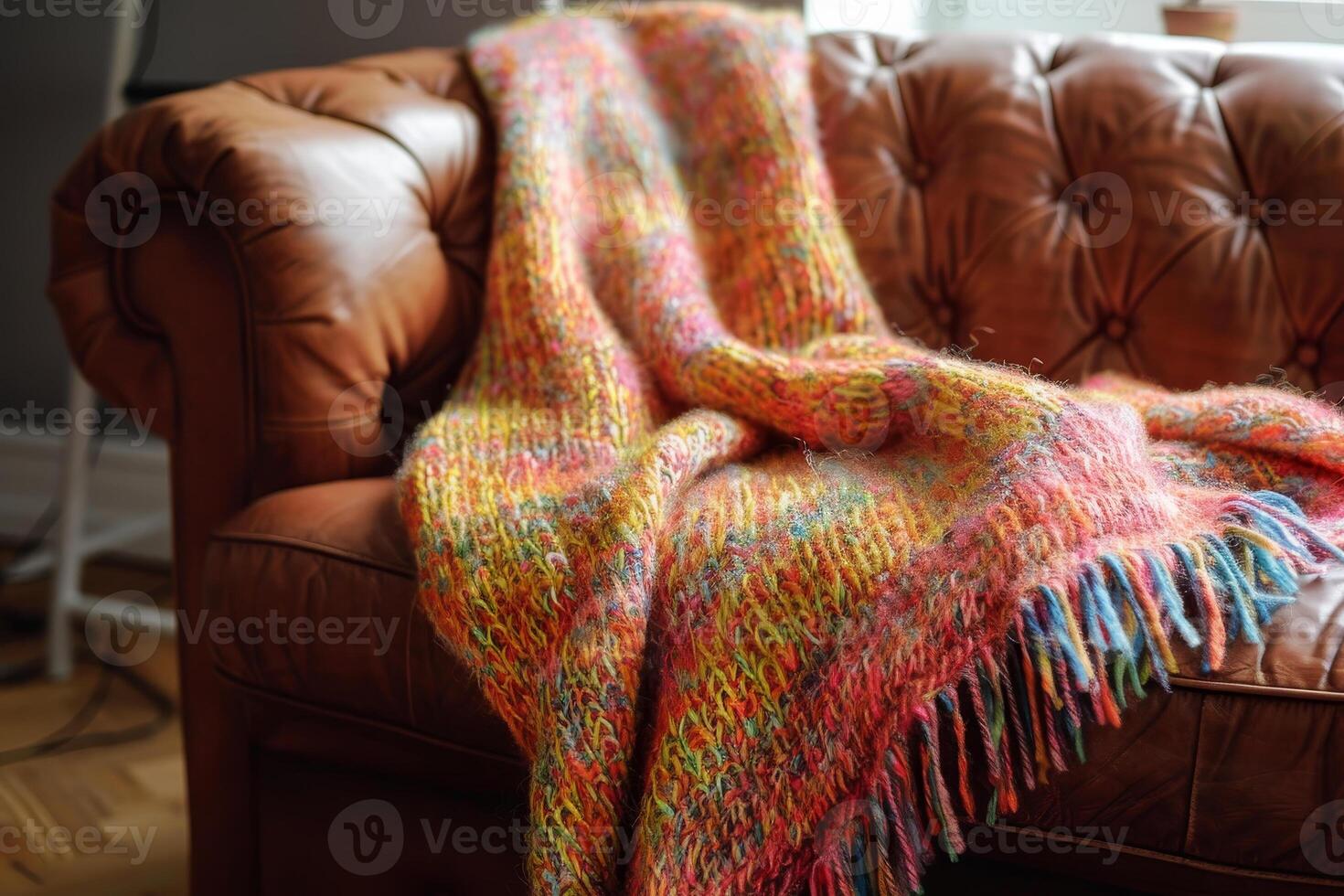 A colorful blanket is draped over a brown couch photo