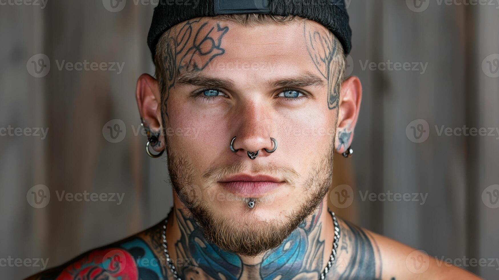 A man with tattoos on his chest and a hat photo