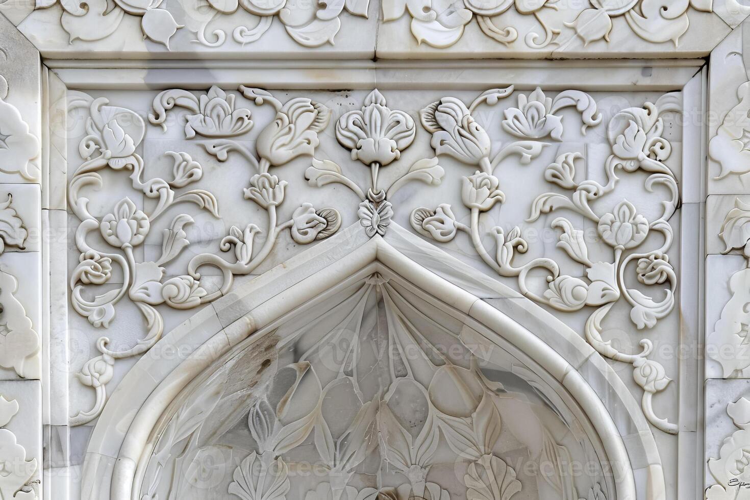 The white marble archway is decorated with floral designs photo