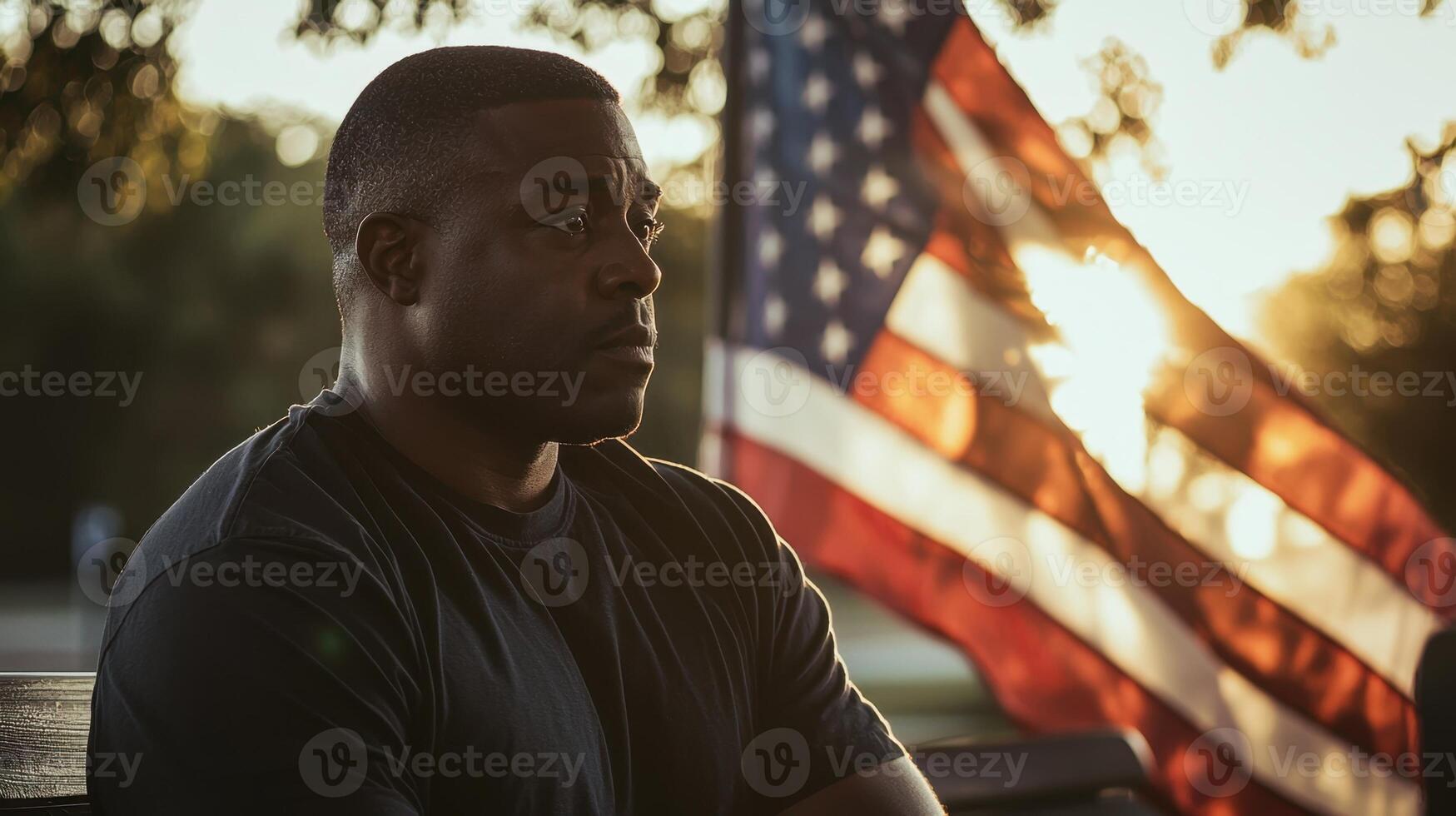 A man sitting on a bench with an american flag in the background photo