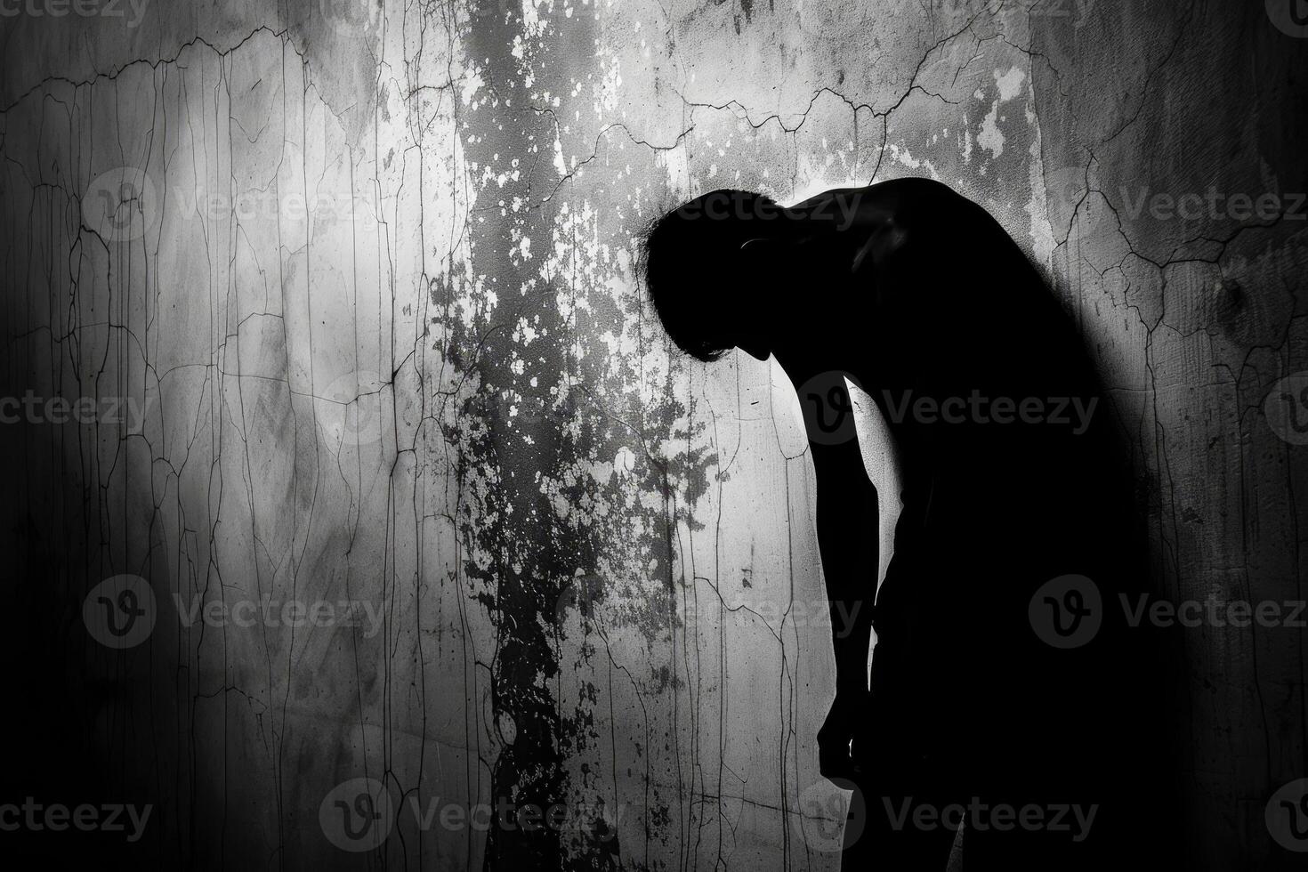 A man is leaning against a wall in a dark room photo