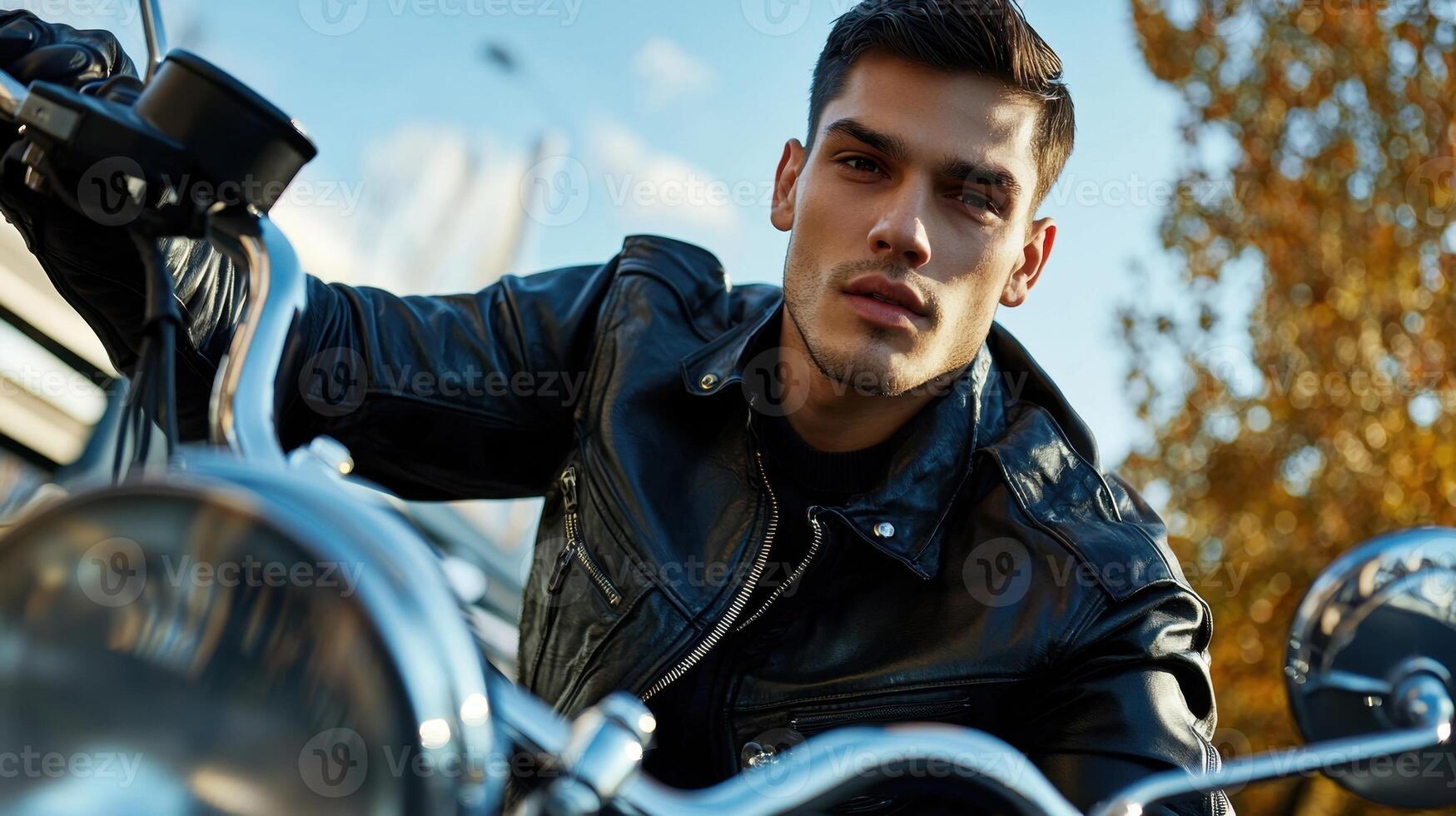 A man in a leather jacket riding a motorcycle photo