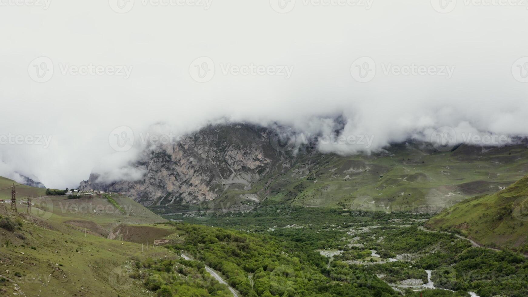 View of a mountain valley with cliffs covered with clouds, forests, fields, roads and residential settlements in the lowlands. mountain nature of the Caucasus photo
