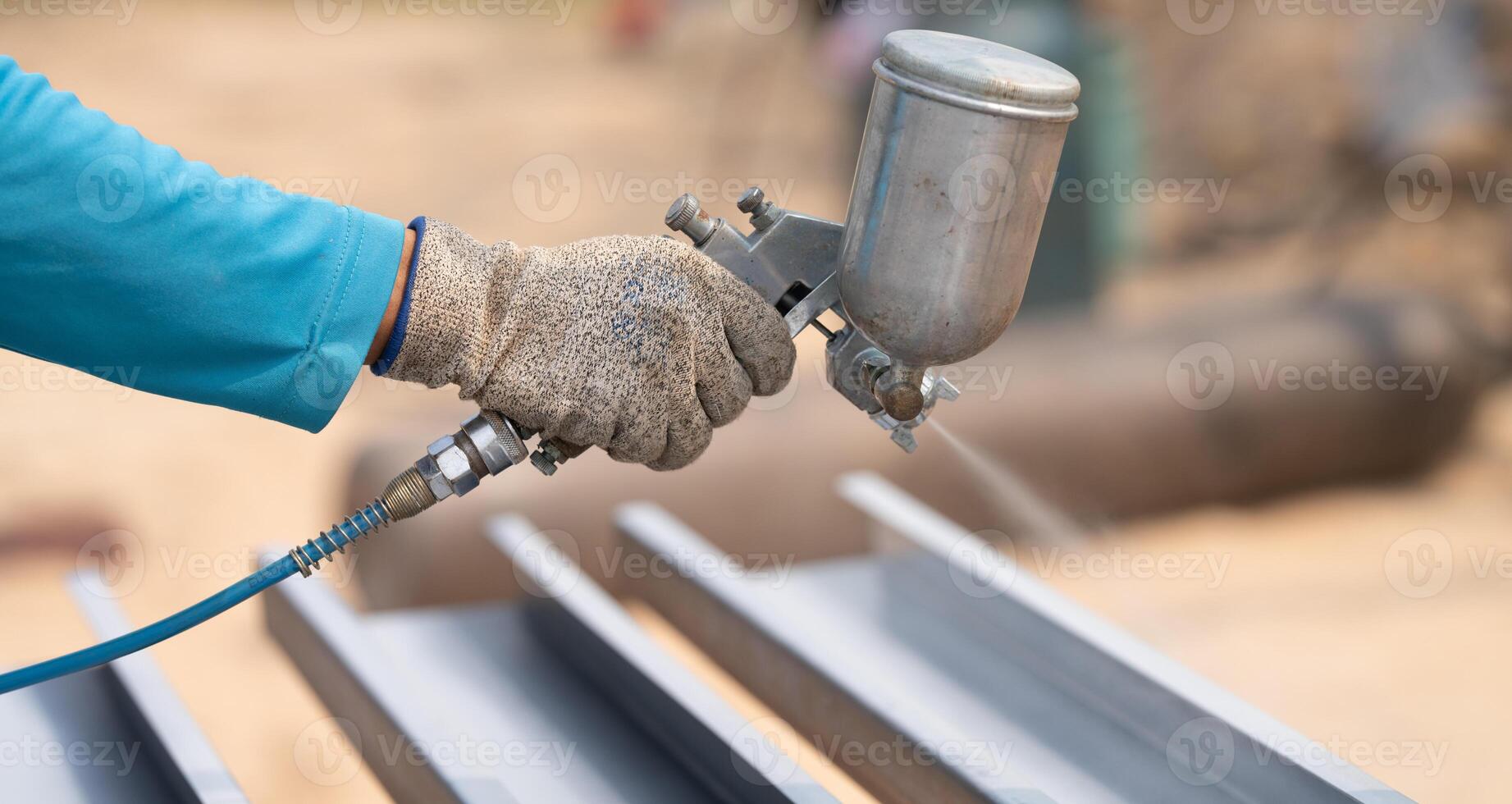 Construction worker painting metal structure surface coating with spray gun at construction site. Metal corrosion and rust protection. Industrial precision. Protective coating to a metal structure. photo