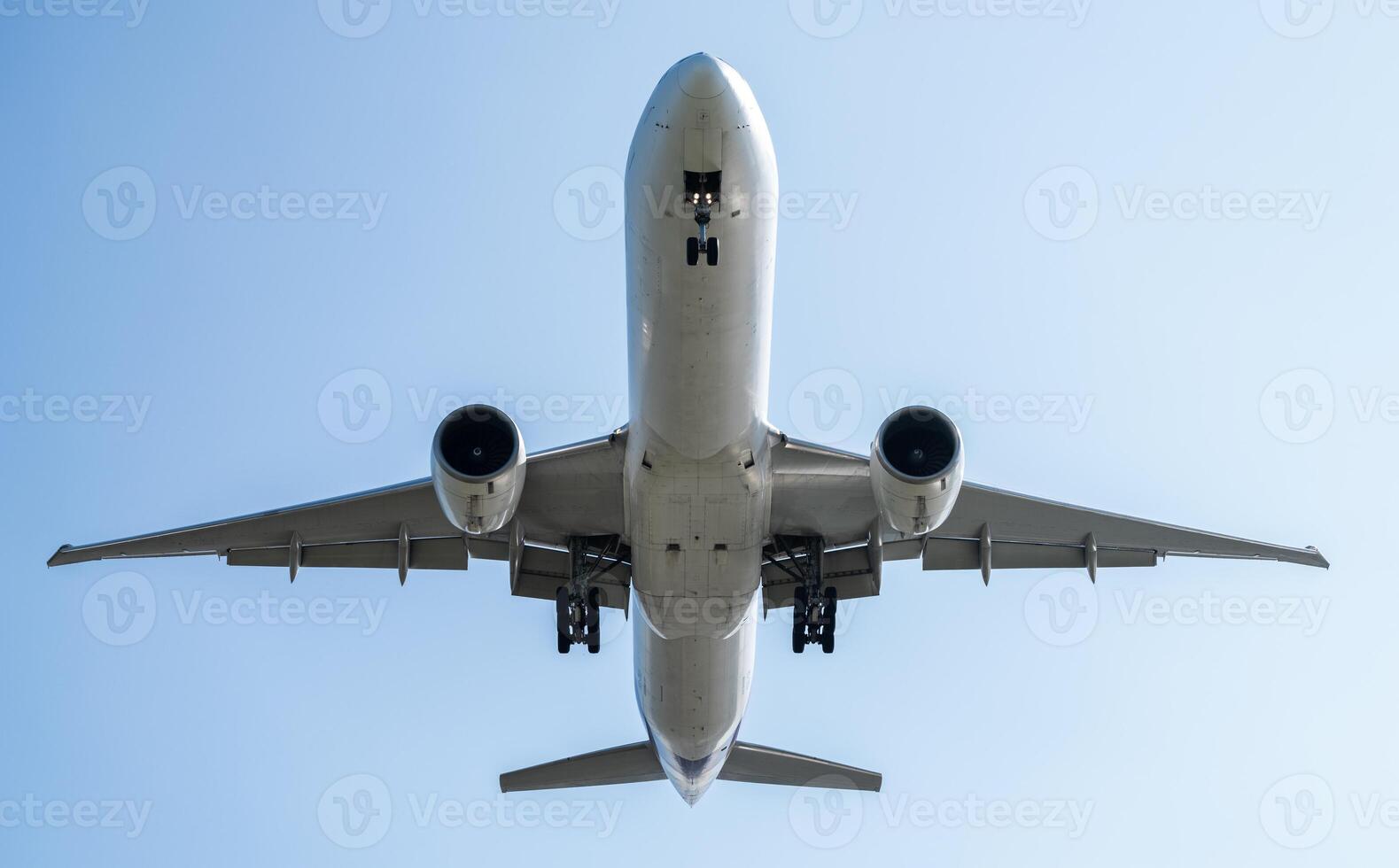 A commercial airplane flying overhead with detailed wings and powerful engines, soaring against a clear blue sky, symbolizing modern aviation, global travel, and the engineering of air transportation. photo