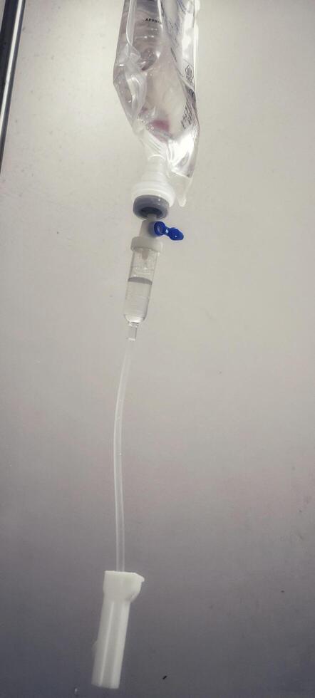 Close up of iv drip against gray hospital wall, highlighting medical equipment used in patient care and treatment photo