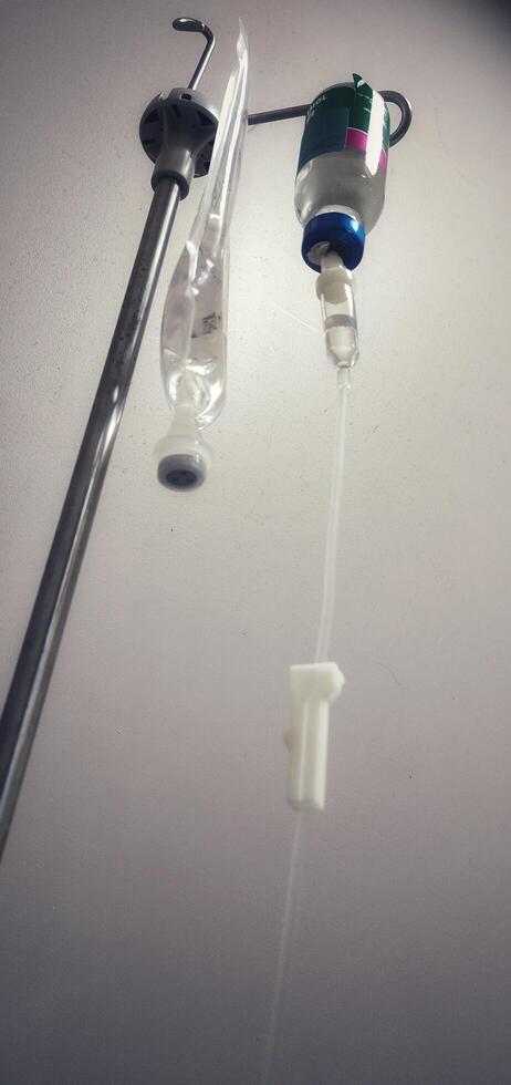 Close-up of iv drip against gray hospital wall, highlighting medical equipment used in patient care and treatment photo