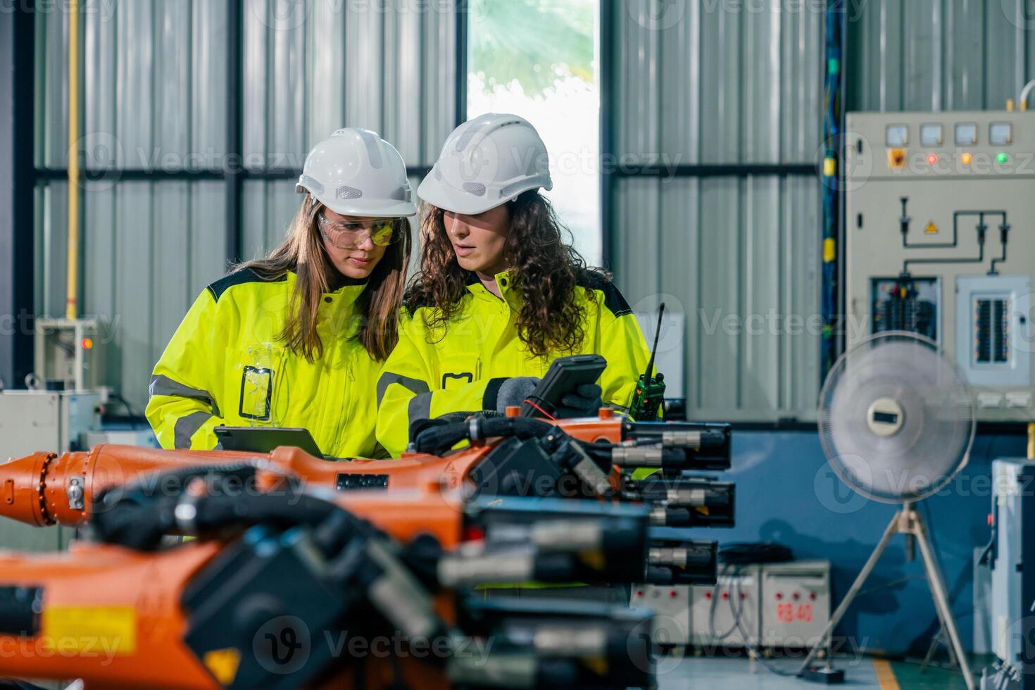 Two engineers collaborating on robotic technology in a modern factory setting during daylight hours photo