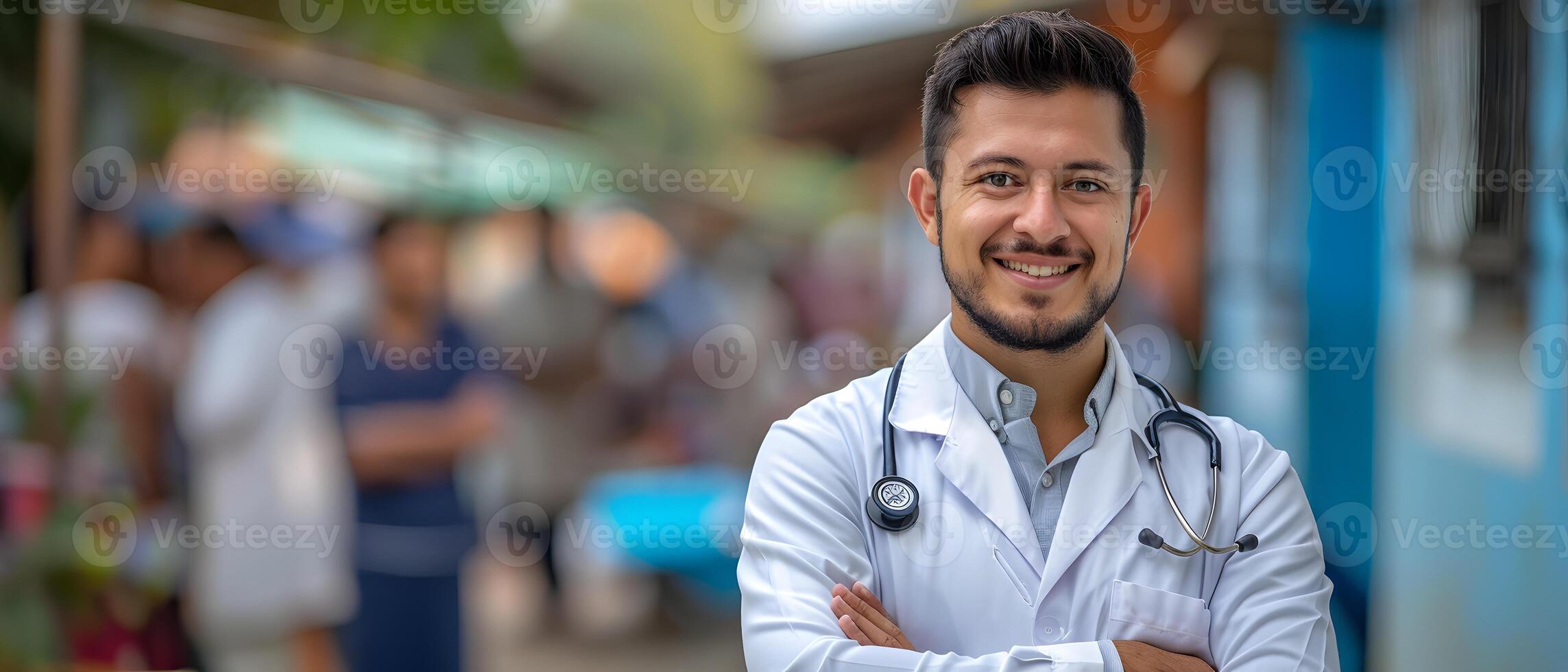 A man in a white coat is smiling and standing in front of a building photo