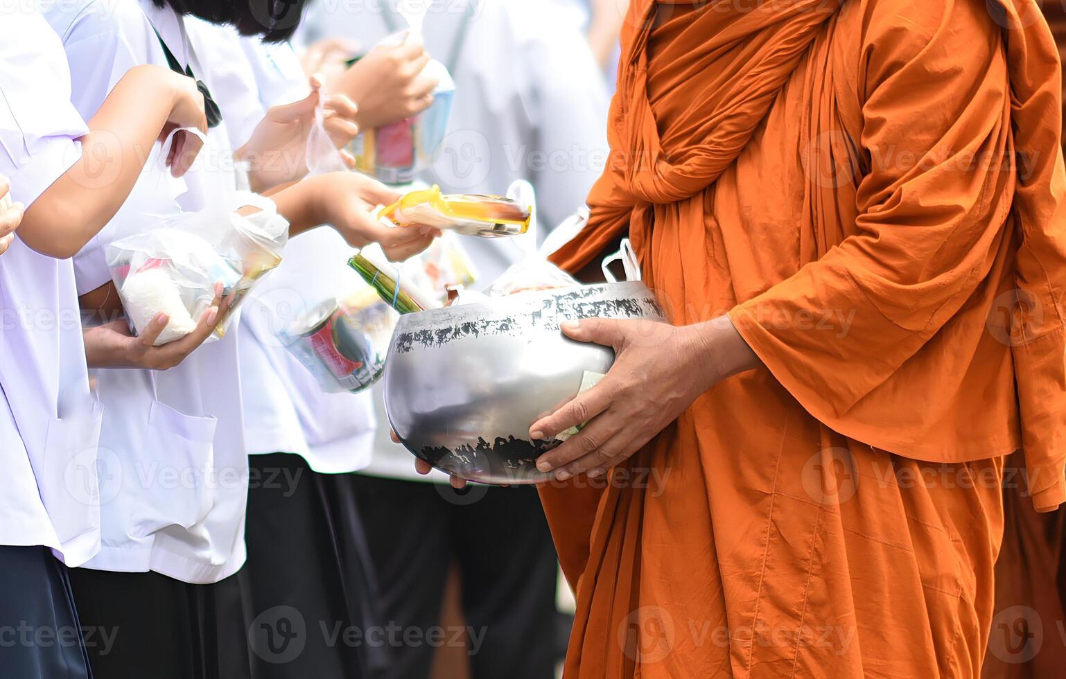 A monk is holding a bowl and giving it to a person.11 photo