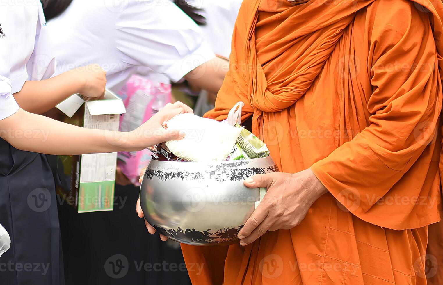 A monk is holding a bowl and giving it to a person.14 photo