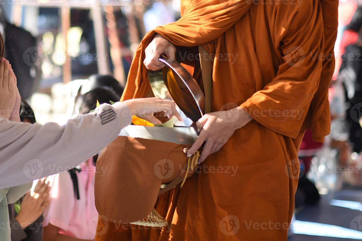 A monk is holding a bowl and giving it to a person.12 photo