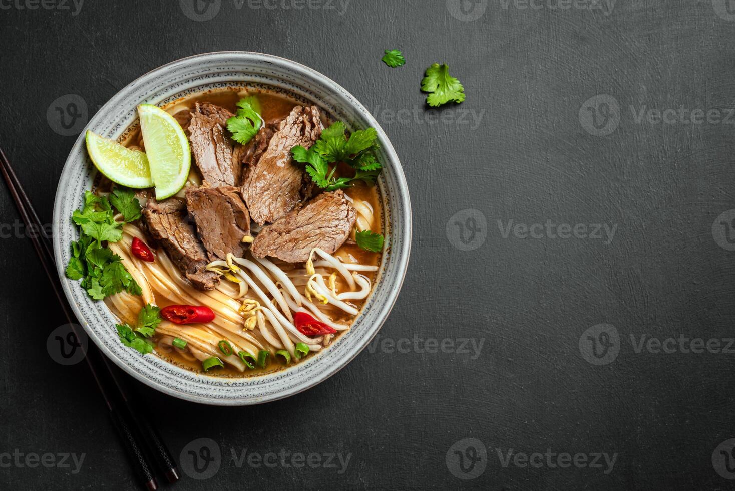 Pho Bo Vietnamese soup with rice noodle and beef on black background photo