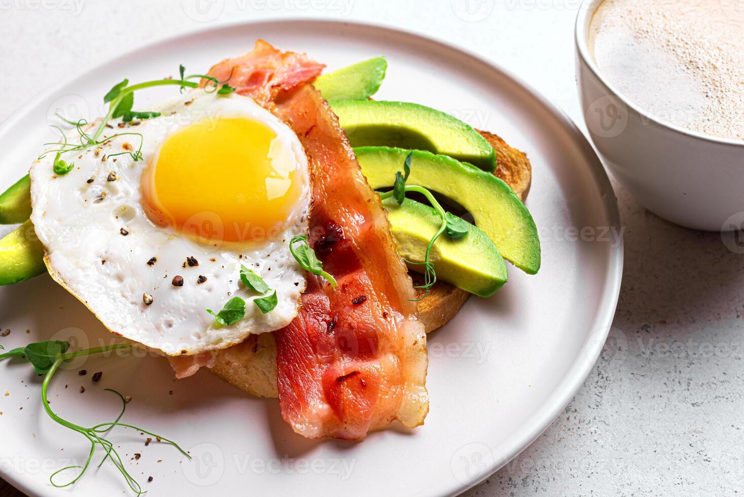 Breakfast toast with fried egg, bacon and avocado closeup photo