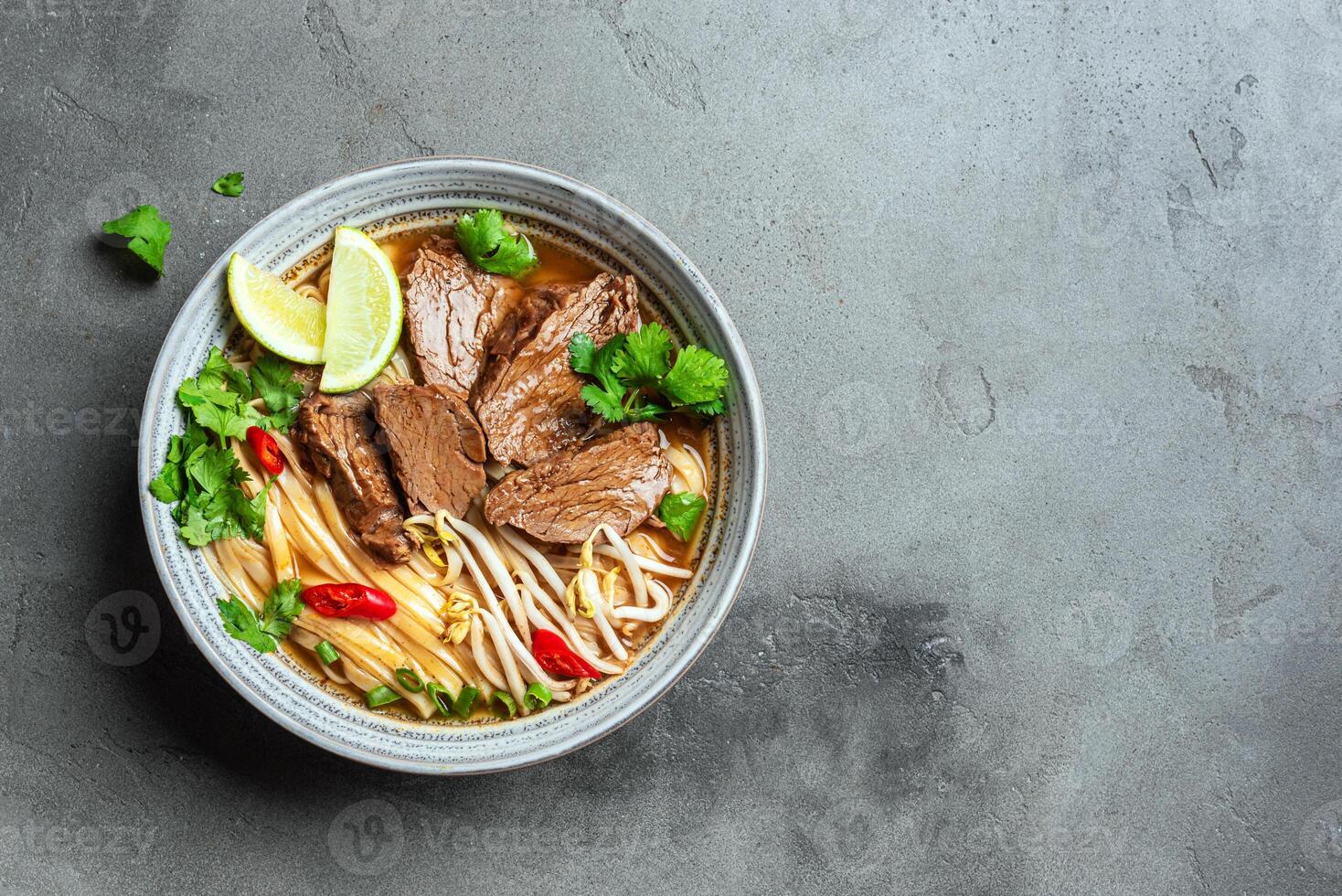 Pho Bo Vietnamese soup with rice noodle and beef on concrete table photo