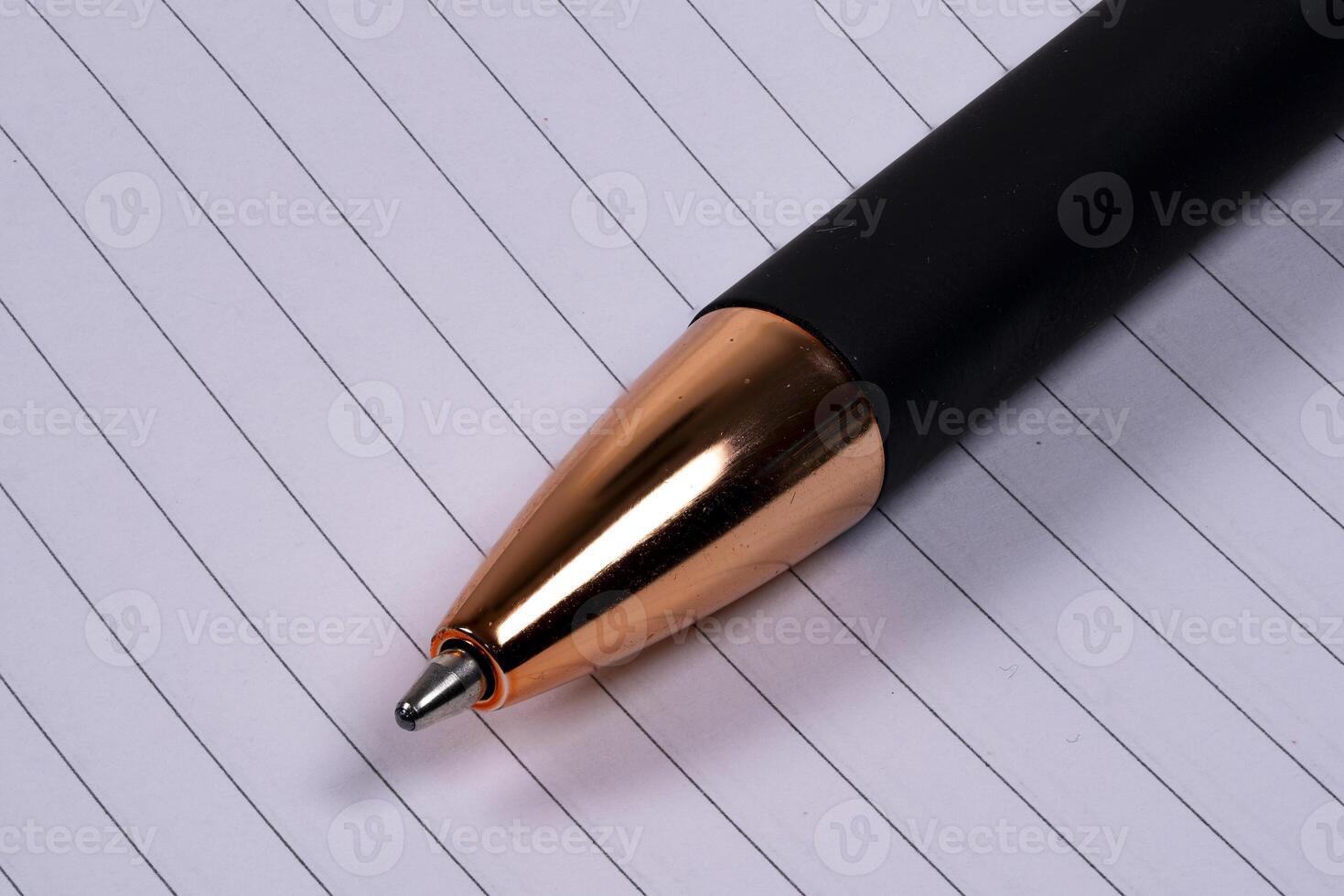 Elegant black and gold pen resting on lined paper sheet photo