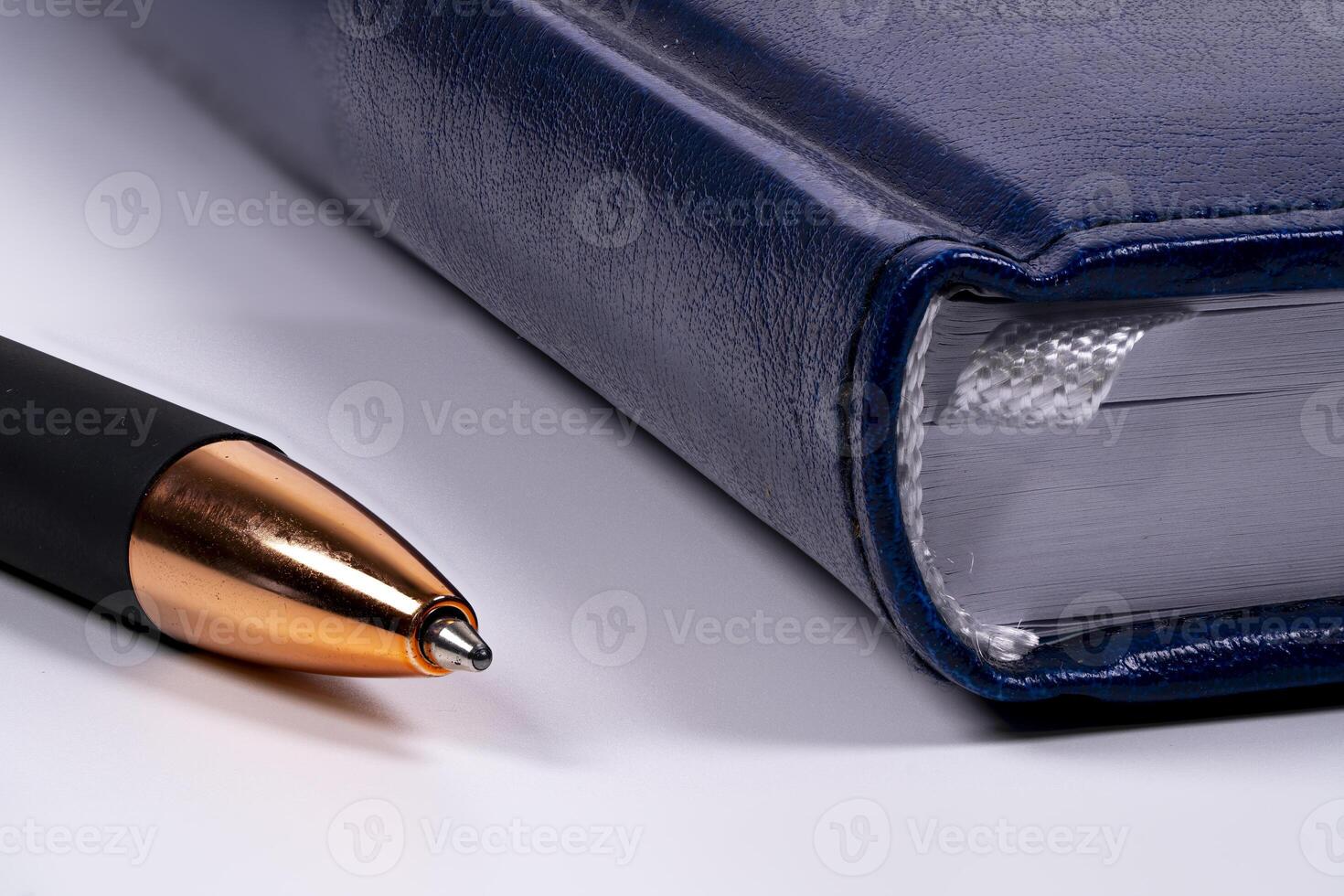 Close-up of a blue notebook and a black pen on a white surface photo