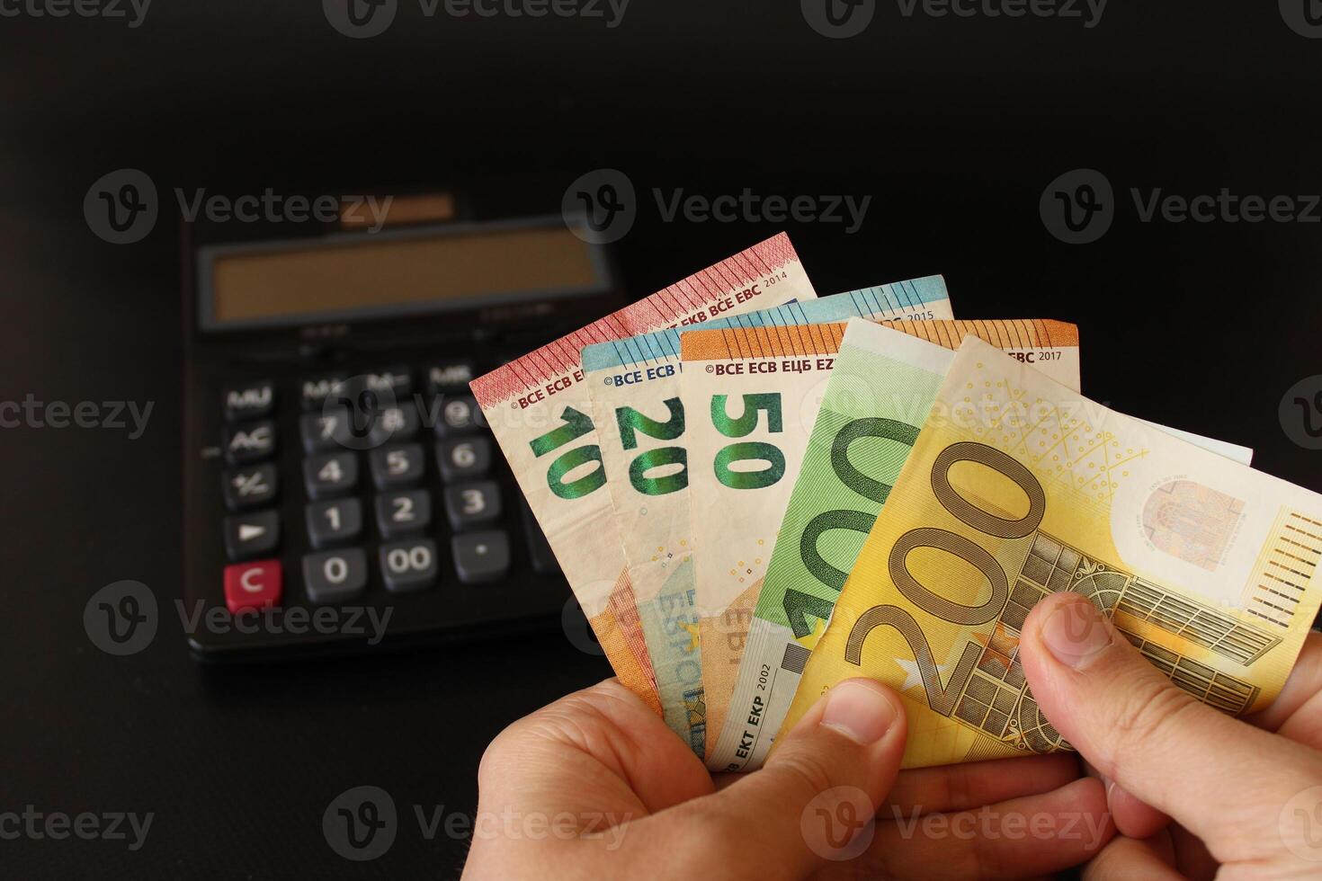 man counting euro money with his hand. euro banknotes. The paper currency of europan union .Calculator in the background. photo