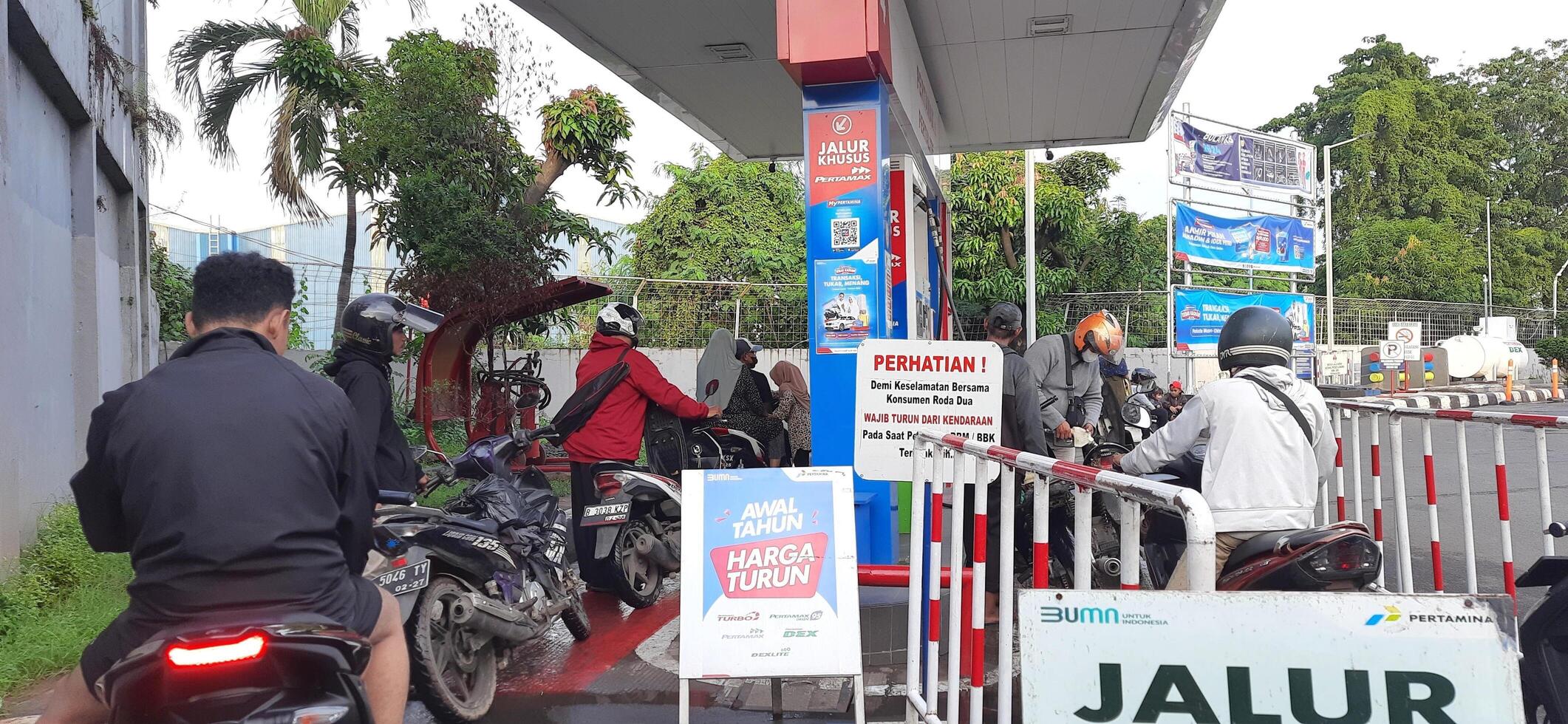 Long queue of motorbike drivers public refueling at Pertamina gas station. Bekasi, West Java, Indonesia - May 22 2024 photo