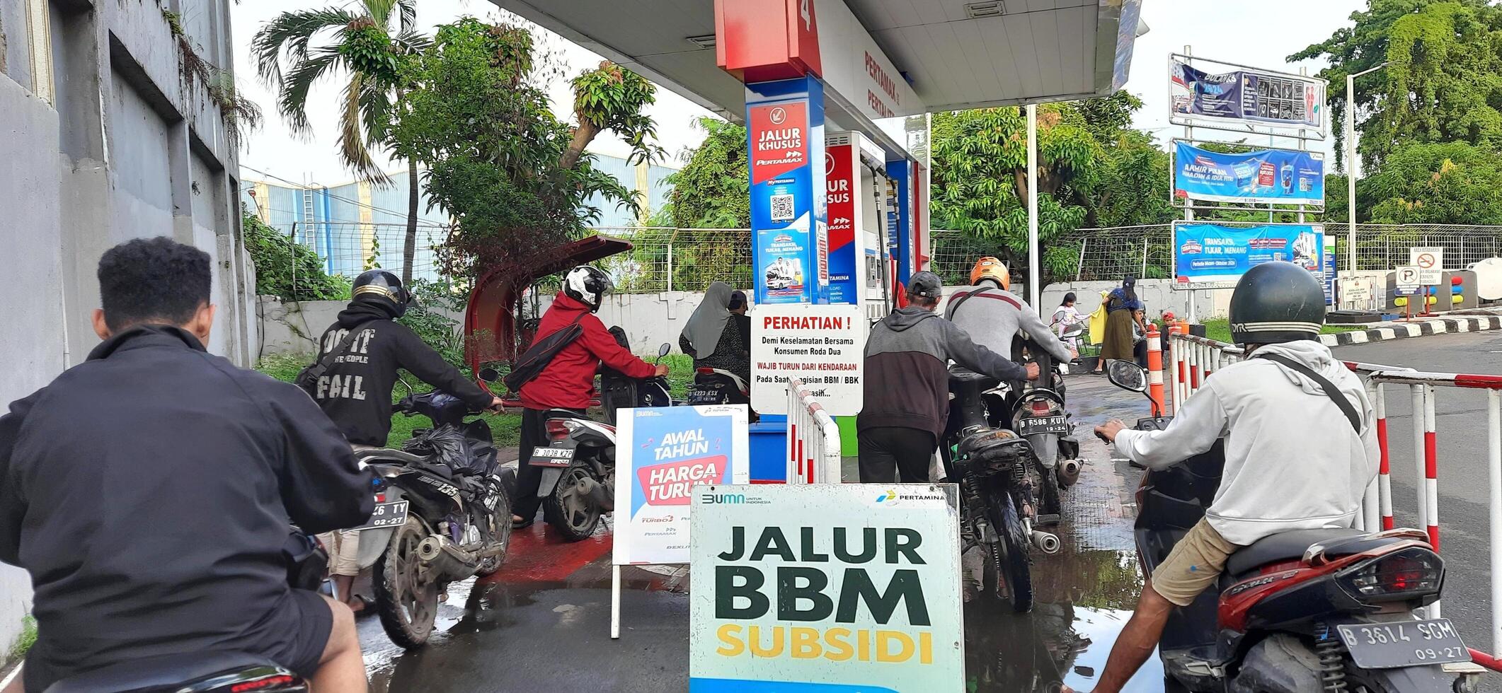 Long queue of motorbike drivers public refueling at Pertamina gas station. Bekasi, West Java, Indonesia - May 22 2024 photo