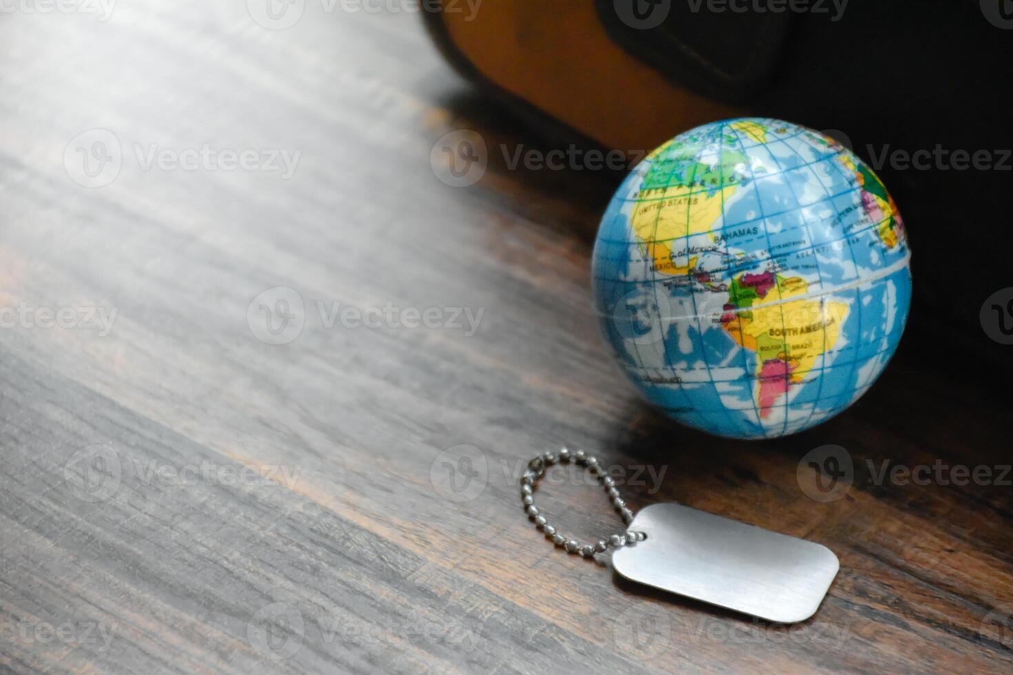 Earth Globe and Dog Tag on wood pattern work desk and soft sunlight background,World and map of Americas,Dog Tag empty,Desktop equipment,Concept of Travel and Work,Top view with copy space,Earth map. photo