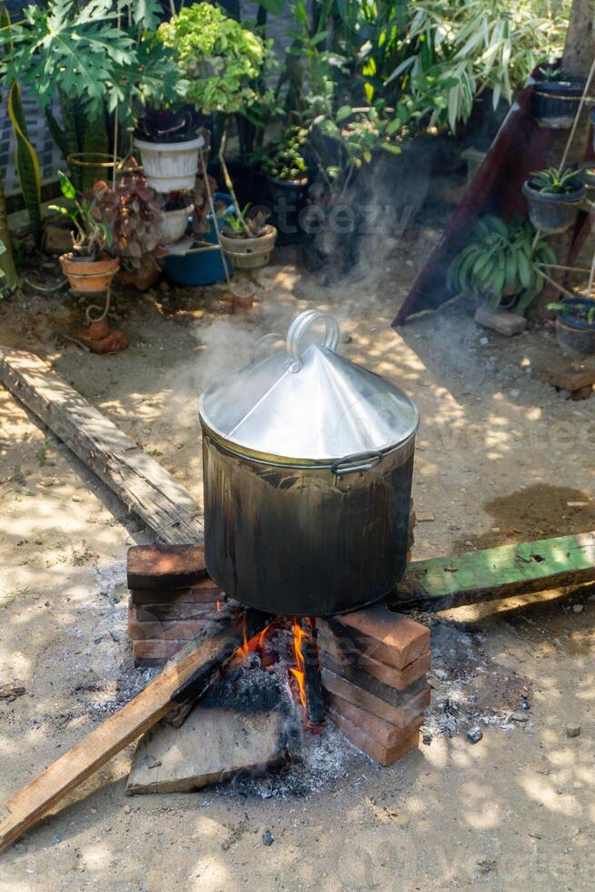 Asian traditional method of cooking. Boiling food with steam boiler and using fire woods. photo