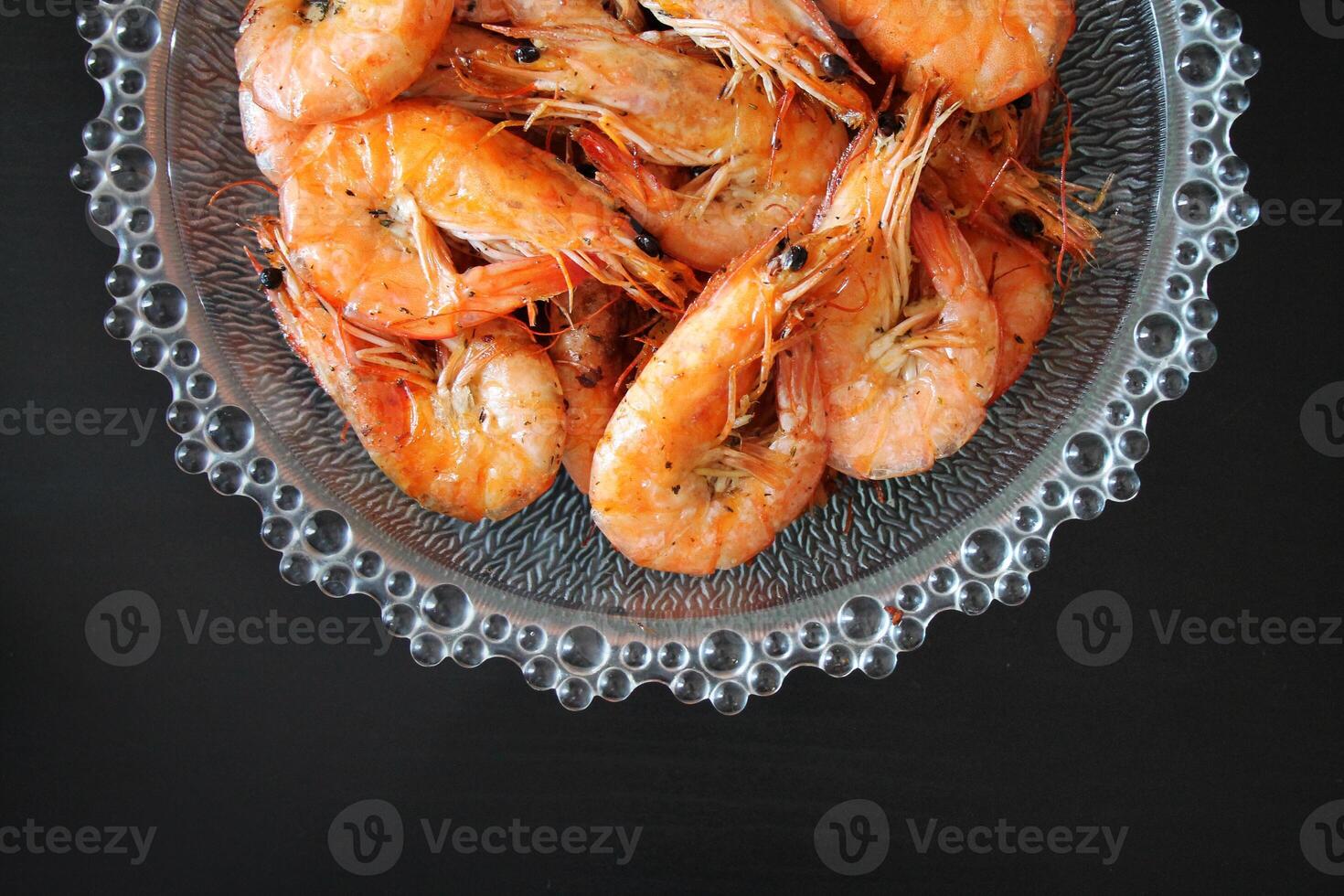 Closeup of cooked shrimp in a glass bowl on a black background. photo