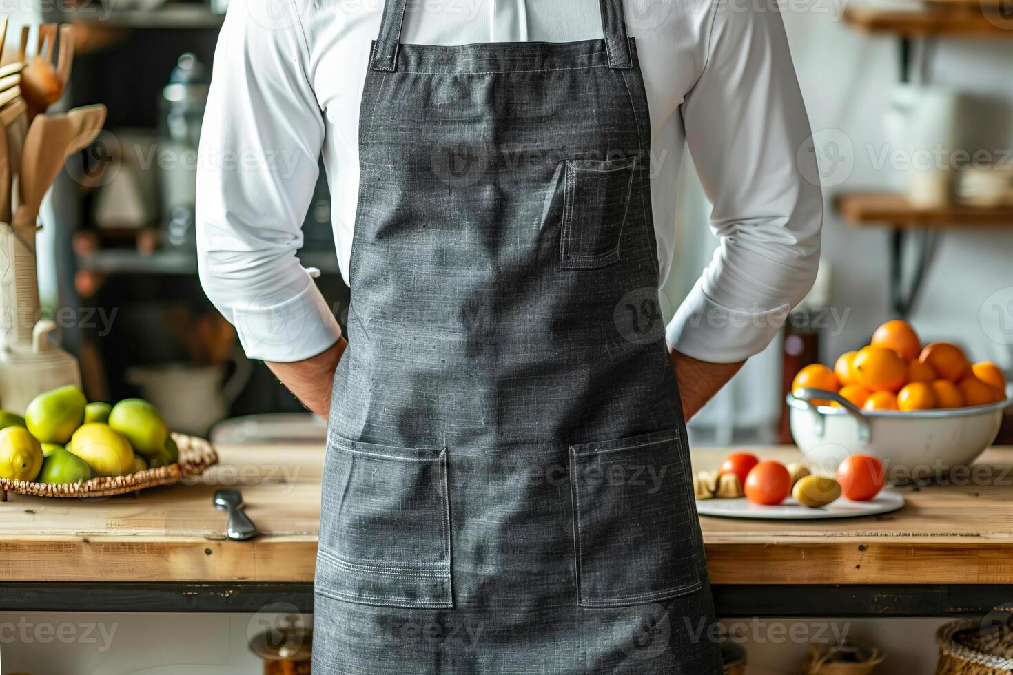 A chef wearing a dark gray linen-cotton apron stands in front of kitchen counter photo