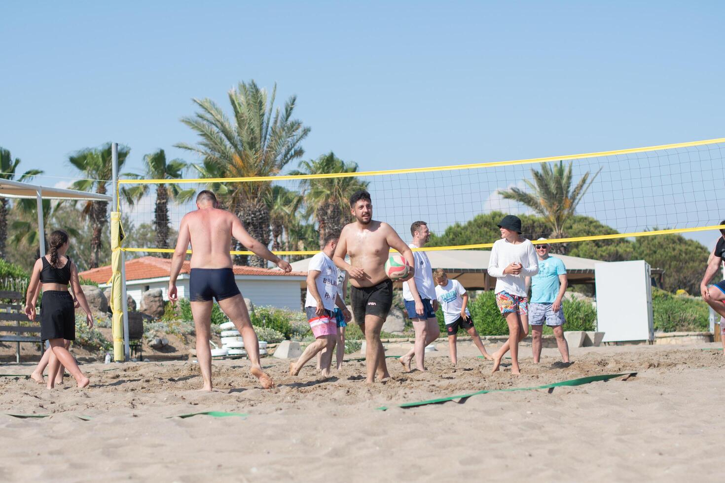vacationing tourists of different ethnic groups play beach volleyball together on the beach by the sea during vacation, throw the ball over the net,Green Max Hotel, Belek, Turkey, May 29, 2024 photo