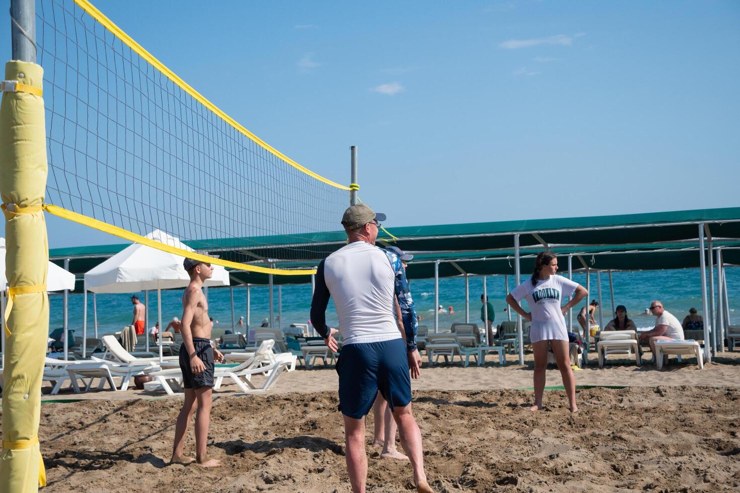 Tourists play beach volleyball on the sea during vacation, background of a clear blue sky while relaxing on the beach of the Green Max Hotel, Belek, Turkey, May 31, 2024 photo