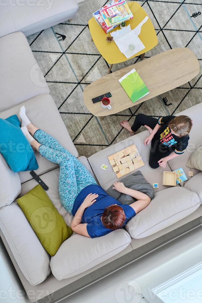 Top View of Mother and Daughter Enjoying a Fun Board Game on the Couch at Home photo