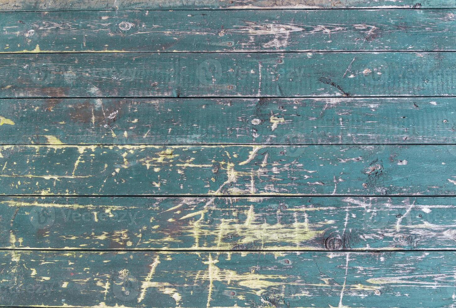 Old wooden surface with rough, worn texture and peeling green paint, horizontal planks with deep scratches highlighting the natural vintage texture of the wood photo
