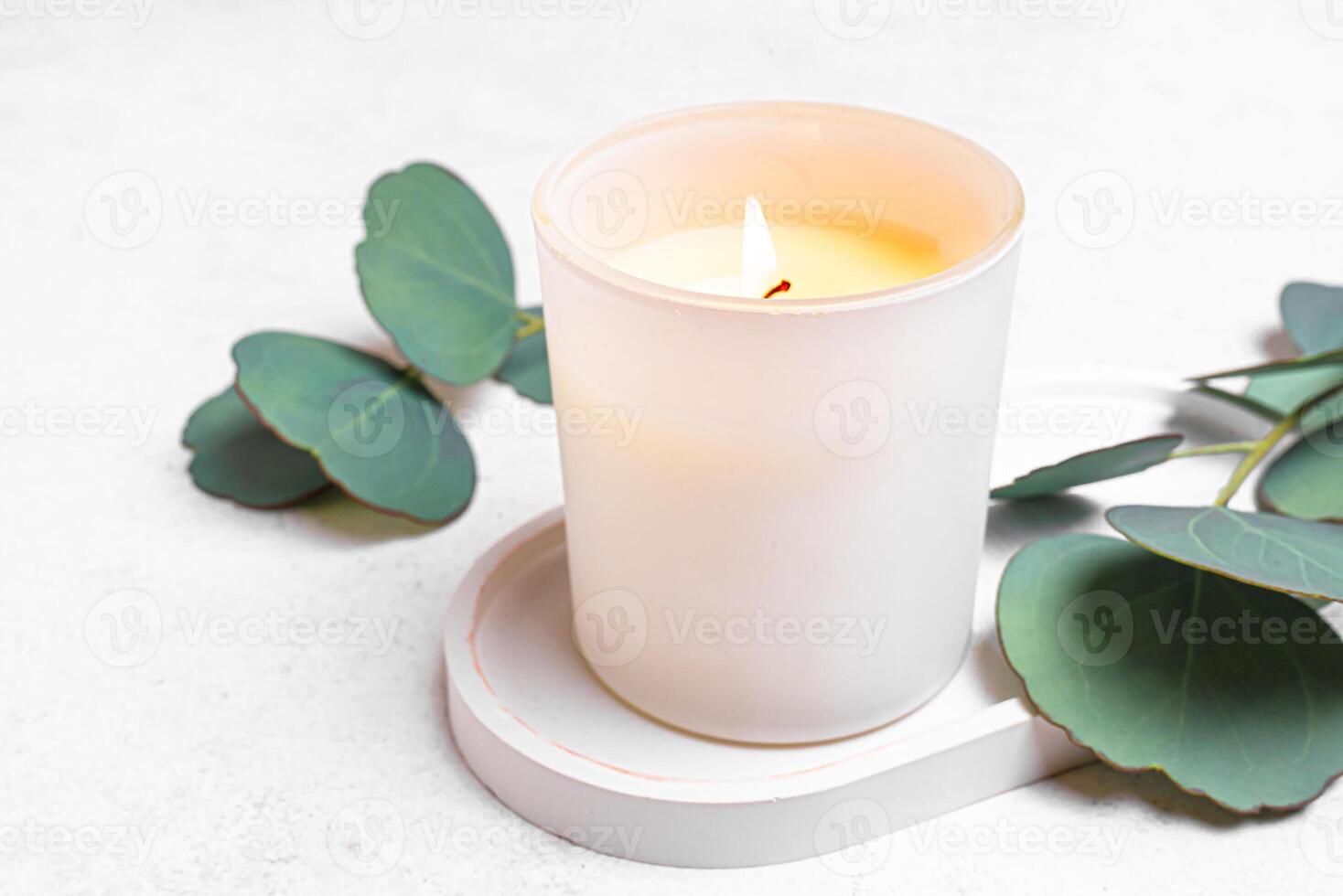 Burning massage candle and eucaliptus leaves photo