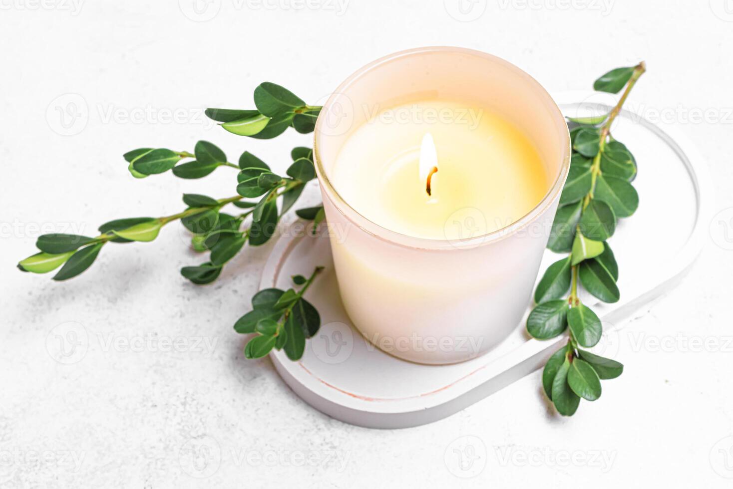 Burning aroma candle and green leaves photo