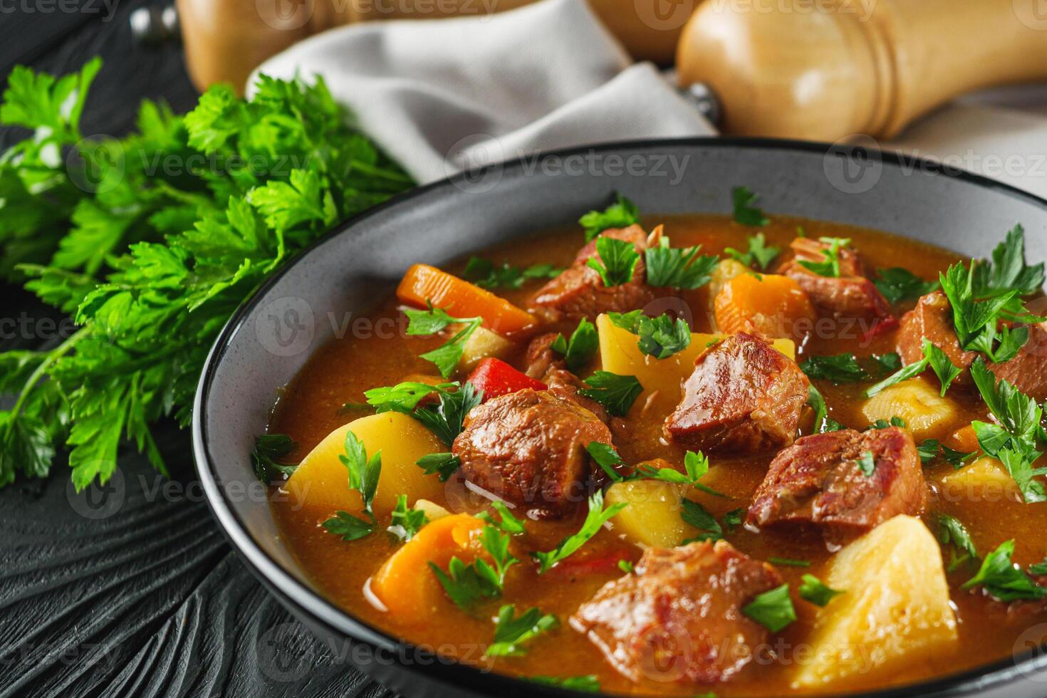 fragrant thick goulash soup on a black wooden rustic background photo