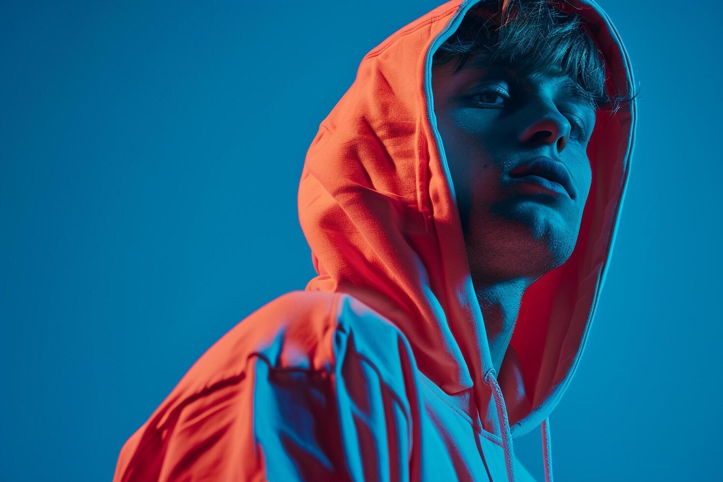Stylish Male Model in Neon Coral Hoodie with Neon Blue Background Bold and energetic Males portrait Highlighting Modern Urban Style photo