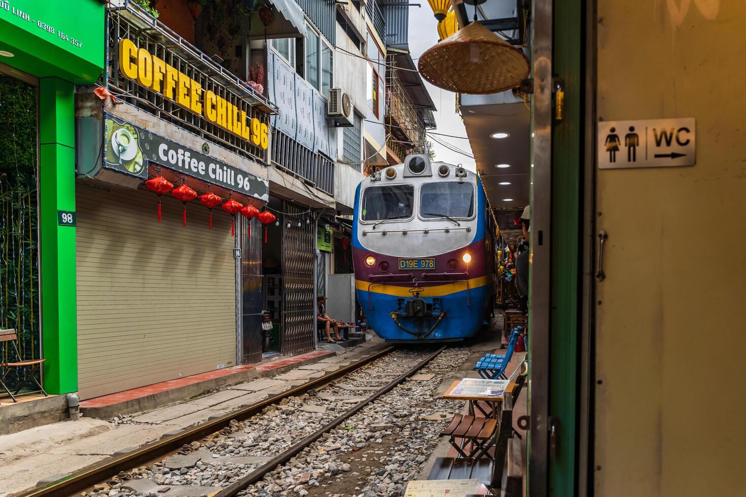 Hanoi, Vietnam - 27 Jun 2024 A train passes through a narrow street in Hanoi's Old Quarter. Tourists take photos of the speeding train. Hanoi's Train Street is a popular tourist attraction.