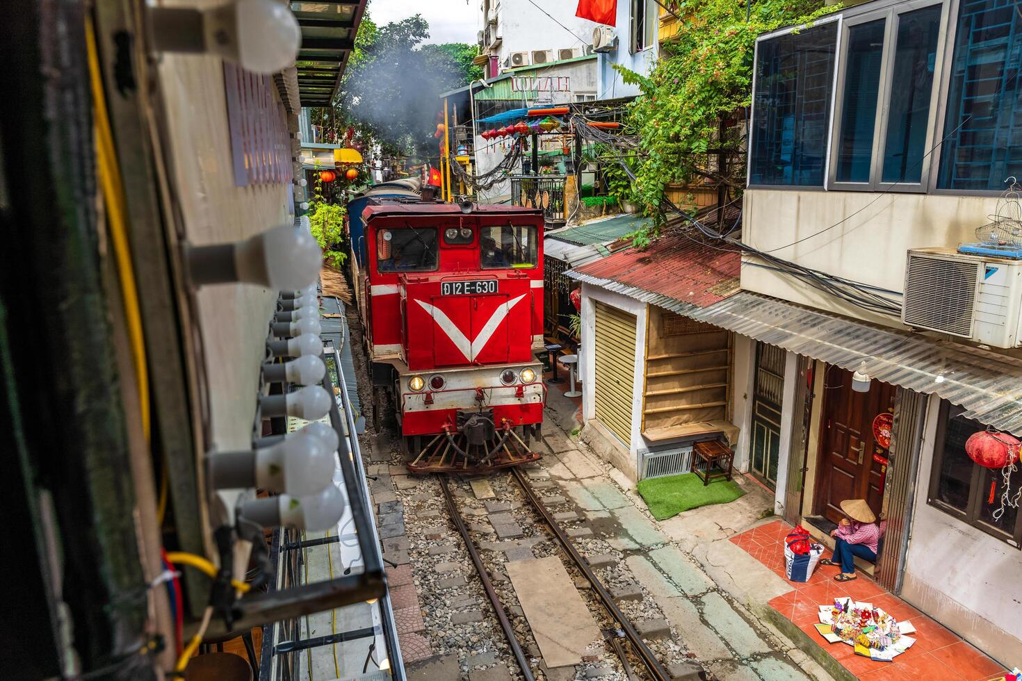 Hanoi, Vietnam - 27 Jun 2024 A train passes through a narrow street in Hanoi's Old Quarter. Tourists take photos of the speeding train. Hanoi's Train Street is a popular tourist attraction.