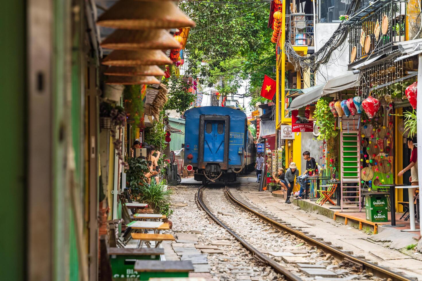 Hanoi, Vietnam - 27 Jun 2024 A train passes through a narrow street in Hanoi's Old Quarter. Tourists take photos of the speeding train. Hanoi's Train Street is a popular tourist attraction.