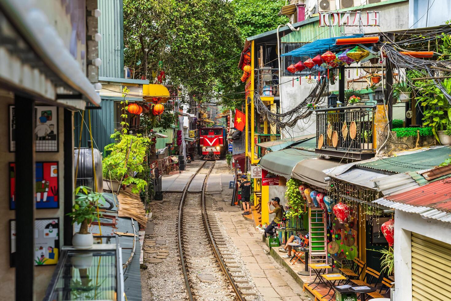 Hanoi, Vietnam - 27 Jun 2024 A train passes through a narrow street in Hanoi's Old Quarter. Tourists take photos of the speeding train. Hanoi's Train Street is a popular tourist attraction.