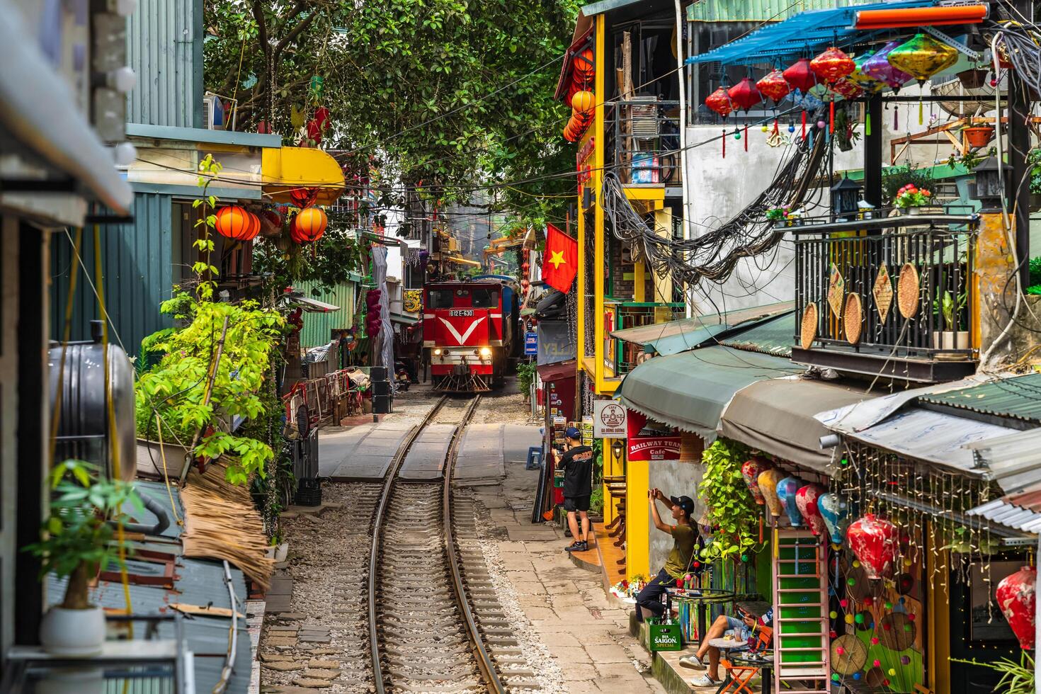 Hanoi, Vietnam - 27 Jun 2024 A train passes through a narrow street in Hanoi's Old Quarter. Tourists take photos of the speeding train. Hanoi's Train Street is a popular tourist attraction.