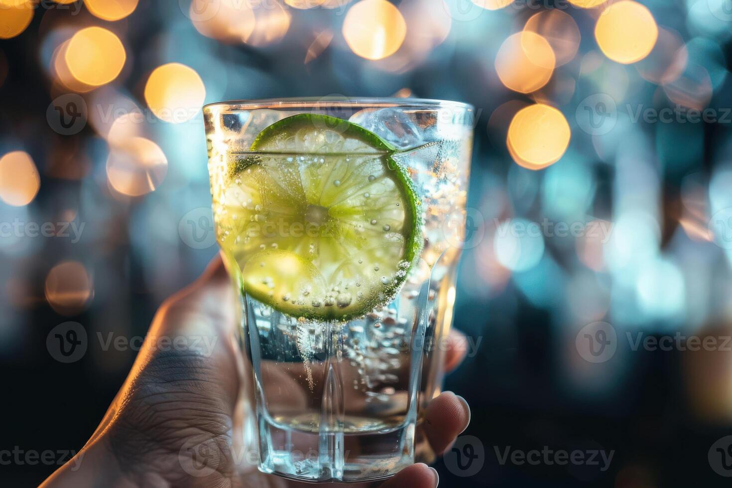 Elegant Glass of Cocktail with Lime and Ice Held in Hand, Ideal for Stylish and Cool Refreshment photo
