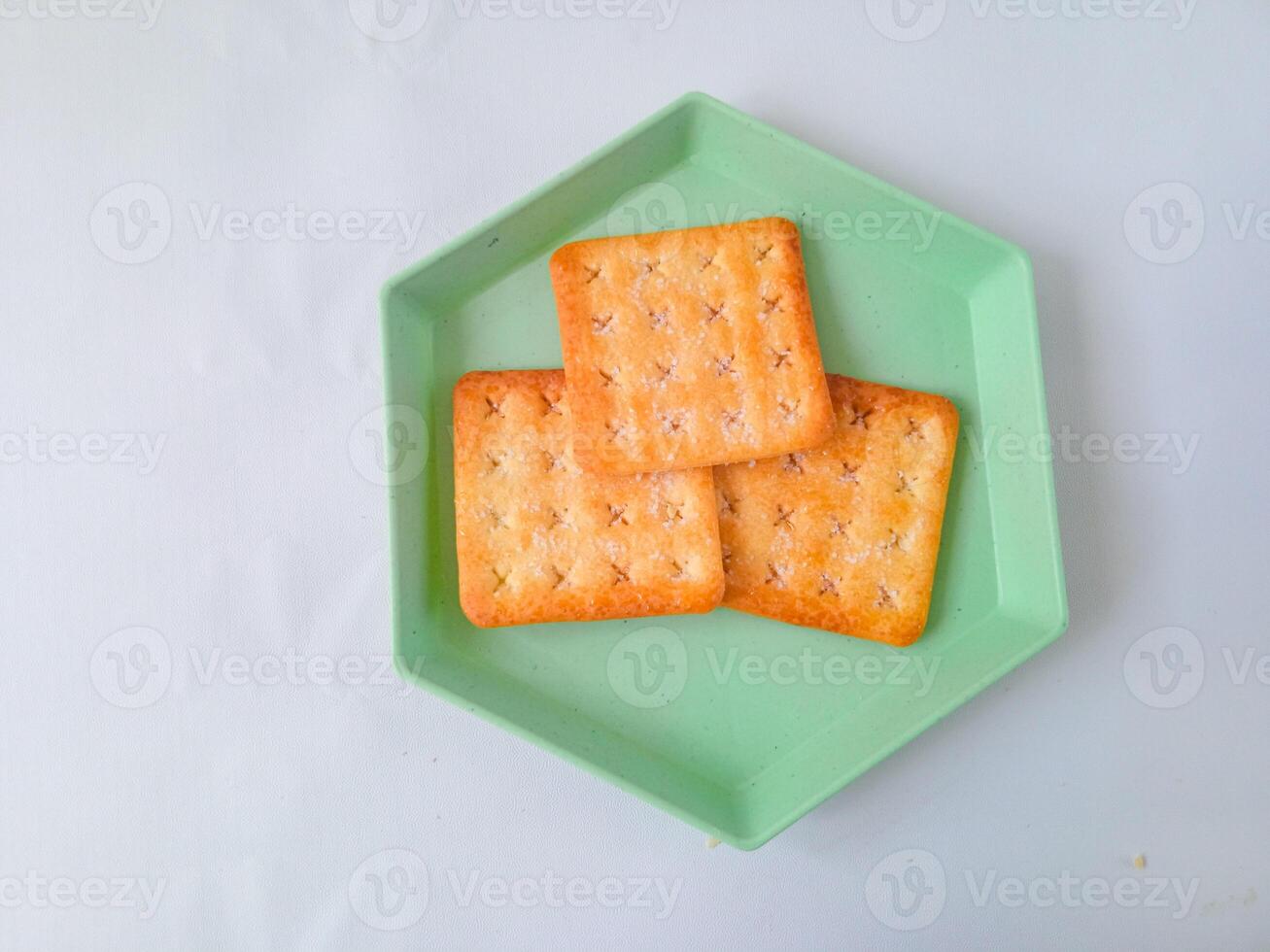 Sugar coated biscuits, also known as malkist, sweet and crispy. on a green hexagon plate isolate on white. snack concept photo