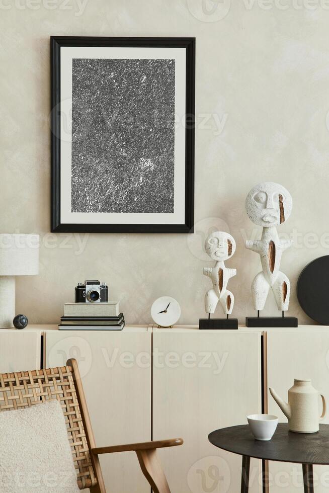 Creative composition of modern beige living room interior design with designed sculptures, mock up poster frame, beige wooden sideboard and personal accessories. . photo