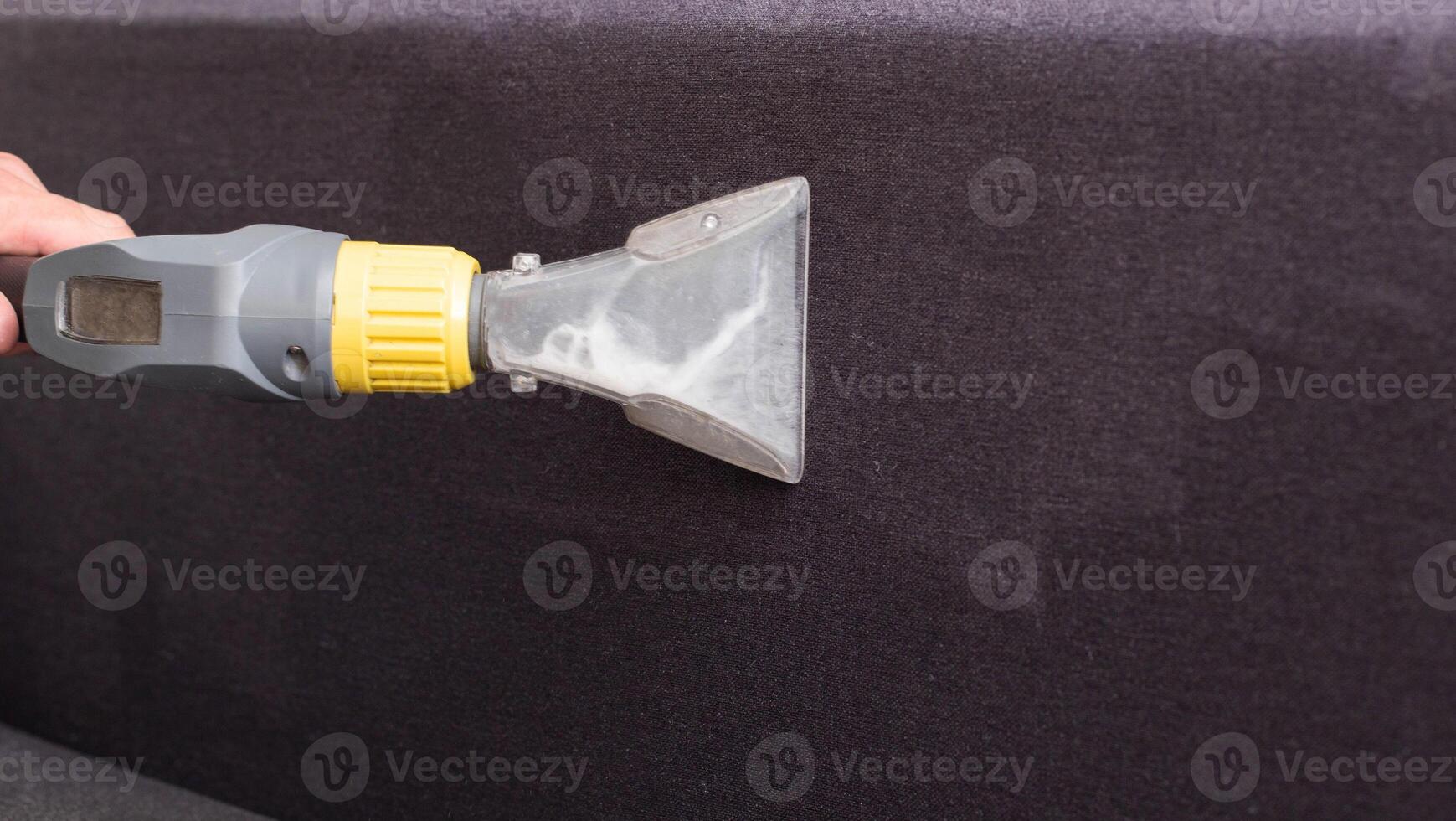Cleaning the sofa with a special washing vacuum cleaner from dirt. Dry cleaning of sofas and upholstered furniture, close-up. Copy space for text photo
